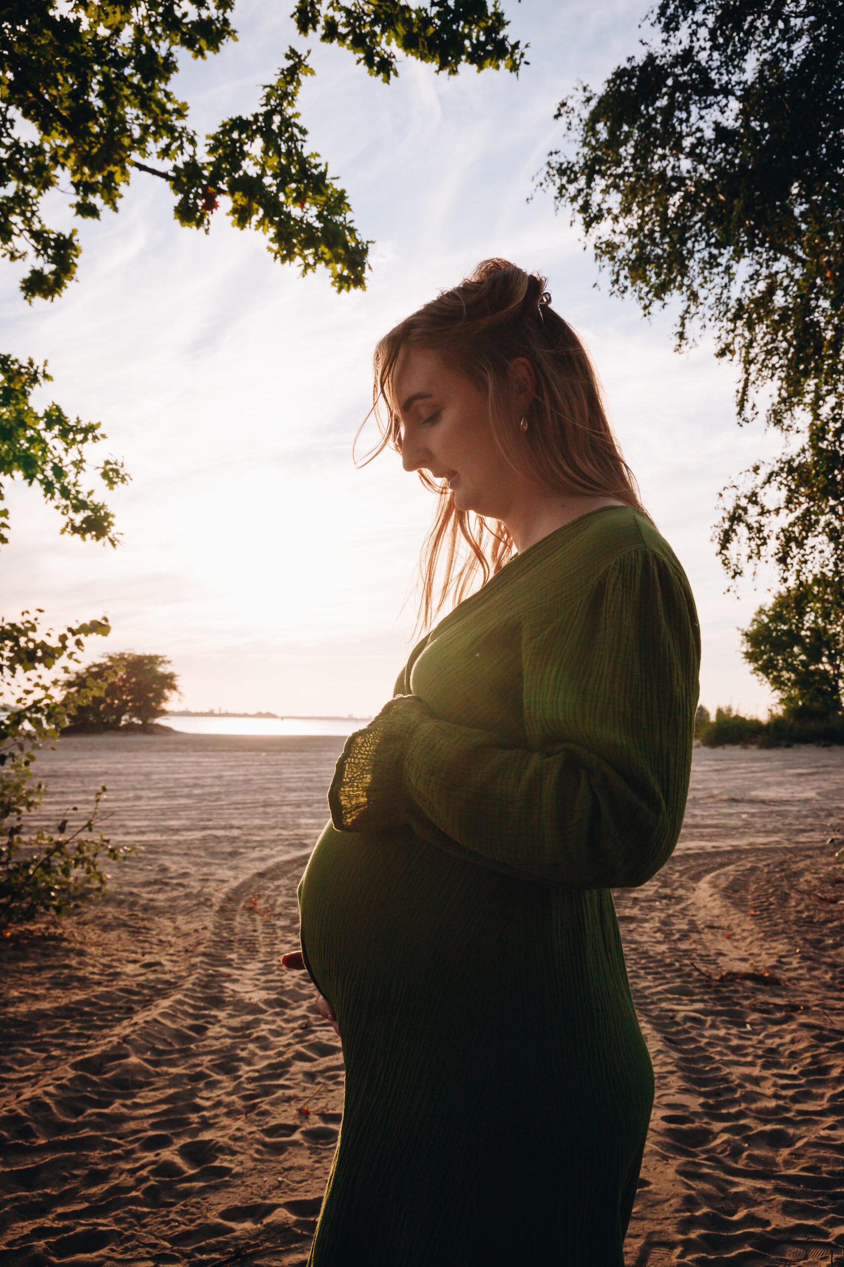 Aanstaande mama zwanger in beeld tijdens zonsondergang op het strand