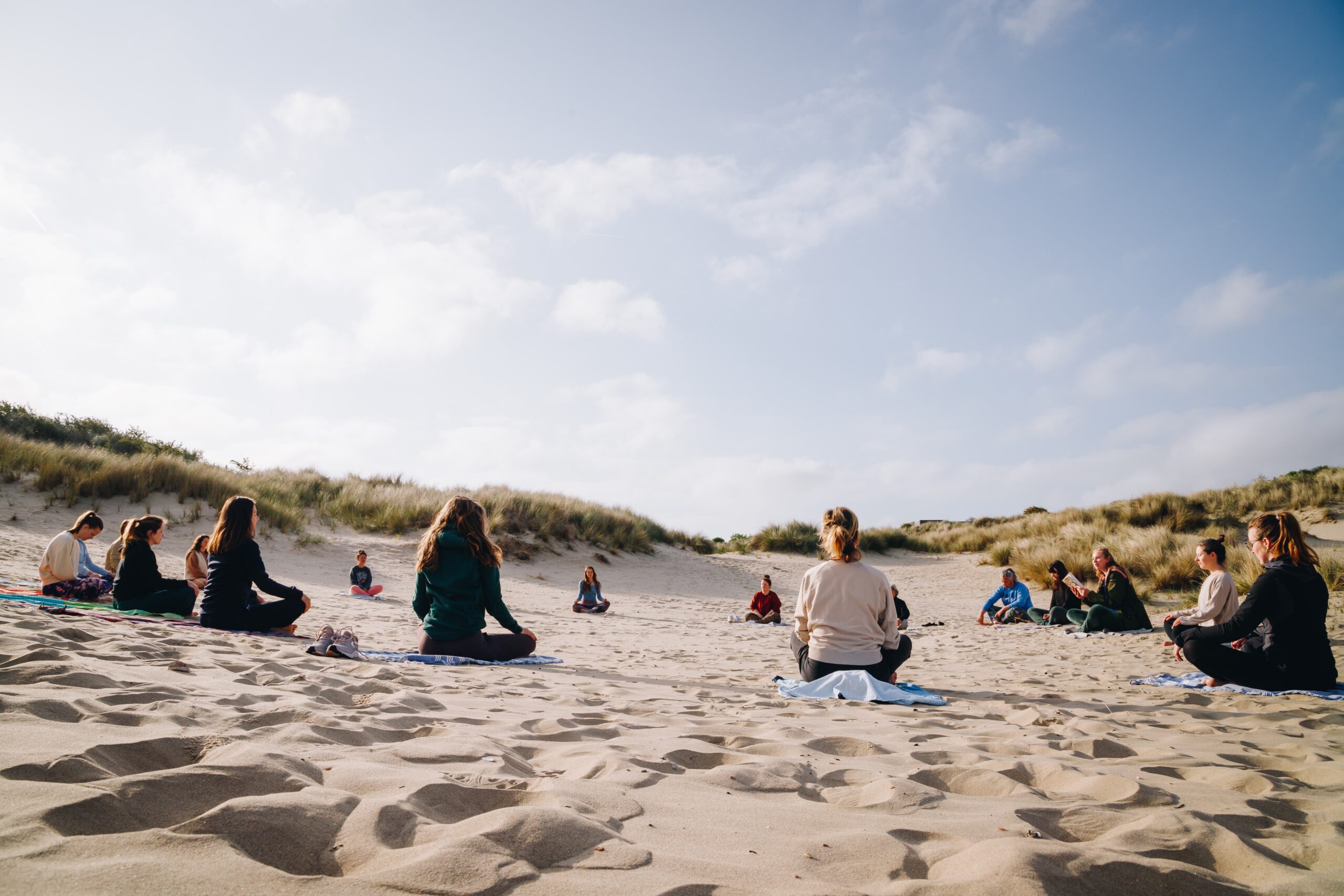 Foto van een groep powervrouwen in een cirkel op yoga matten in de duinen van Den Haag